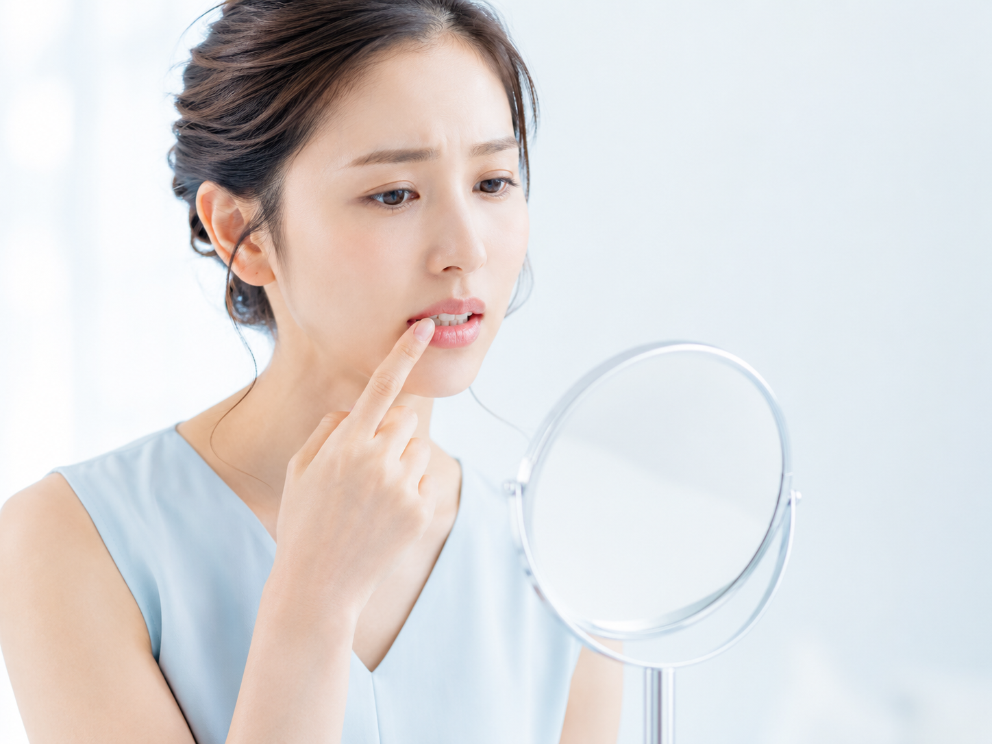鏡を見ながら口元を気にする女性